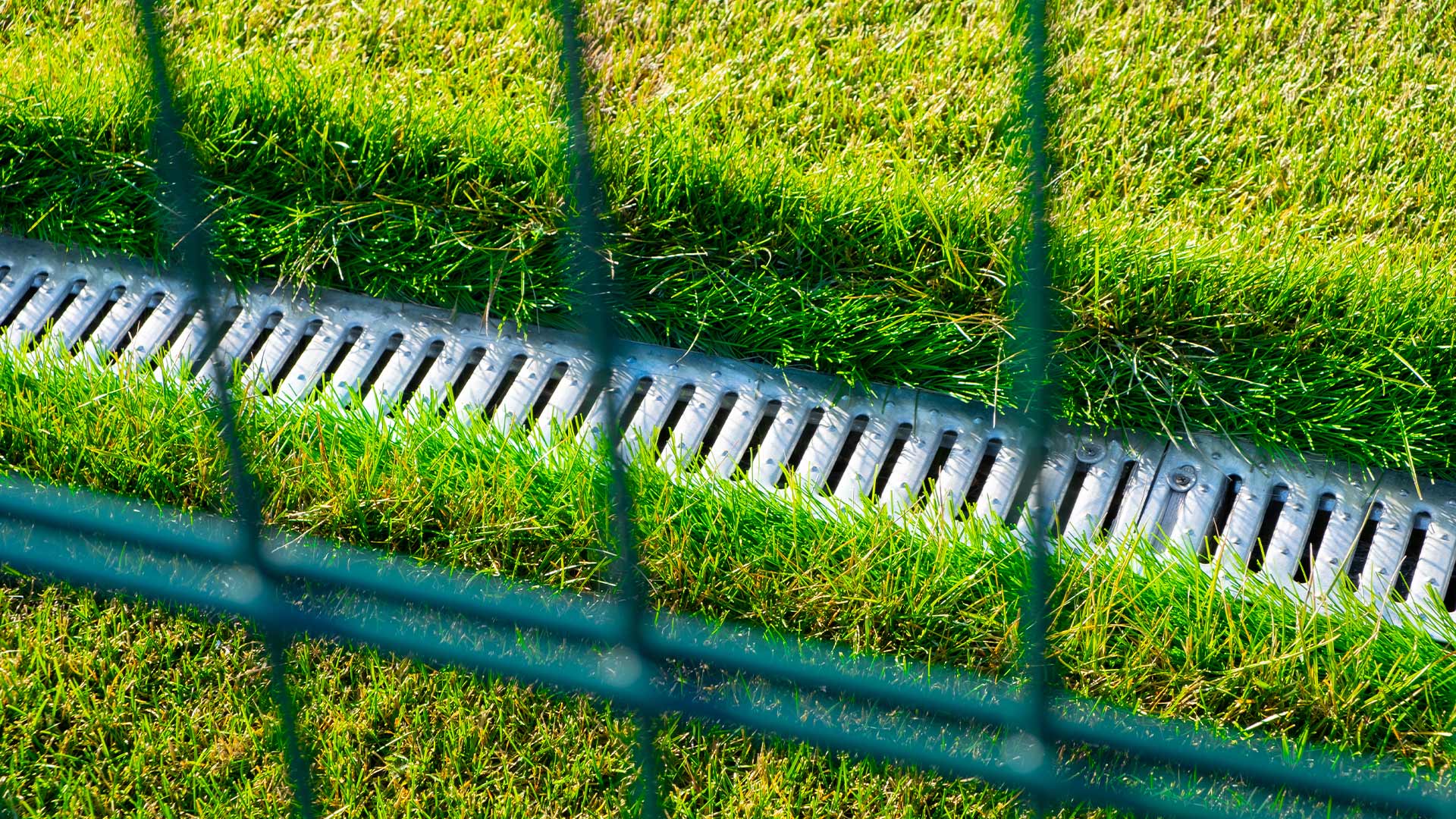 How do you ensure proper drainage on a grass tennis court?